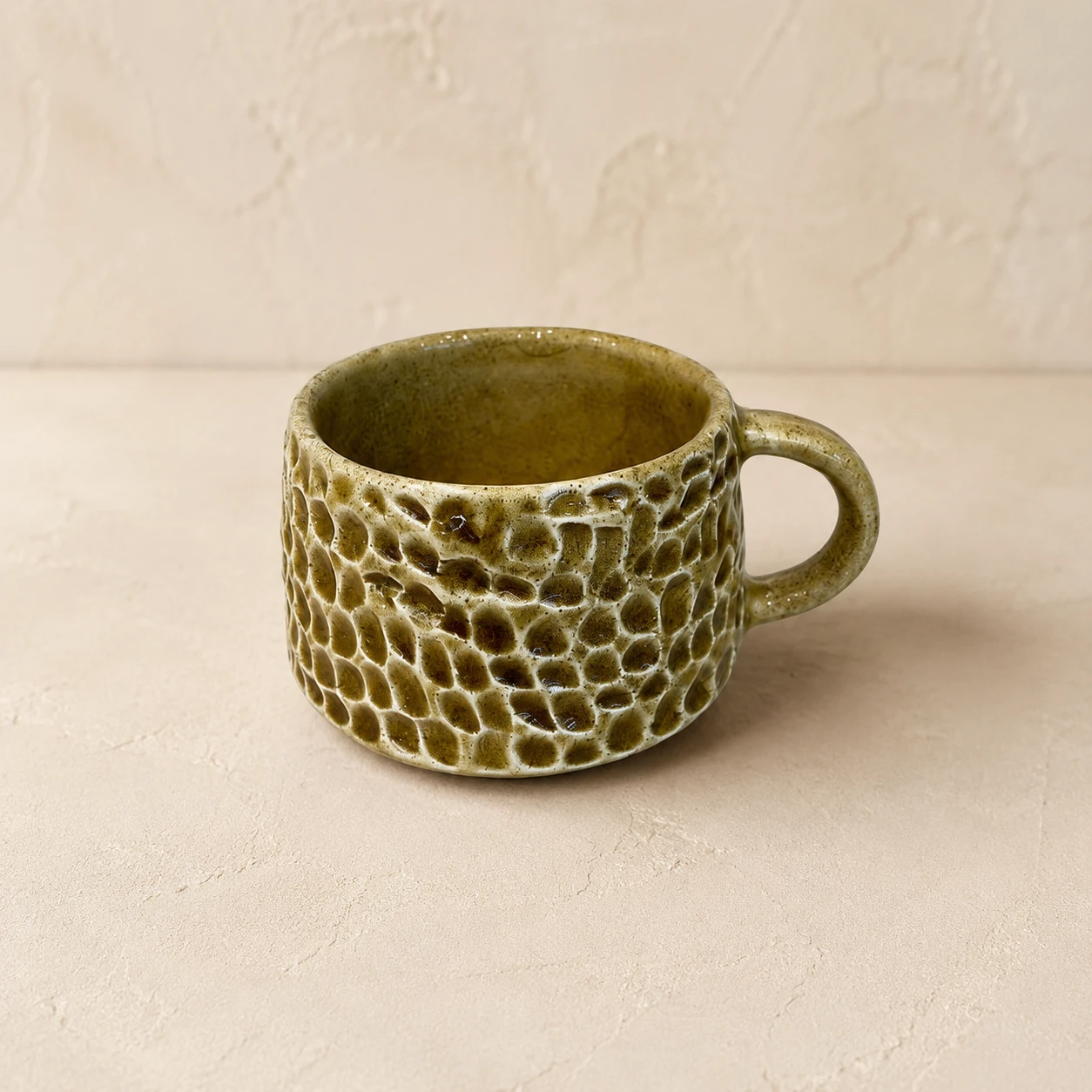 Handcrafted ceramic tea cup with olive green glaze and carved honeycomb texture