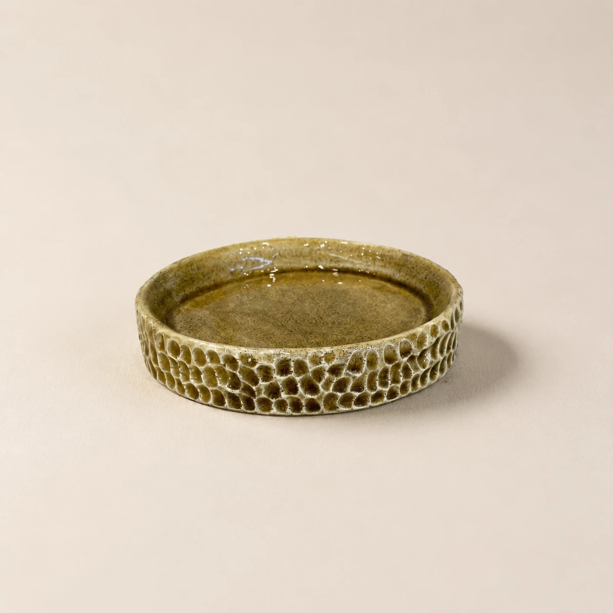 Handcrafted round ceramic dish with olive green glaze and carved honeycomb texture
