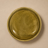Side view of a handmade ceramic dish with organic carved surface and rustic detail