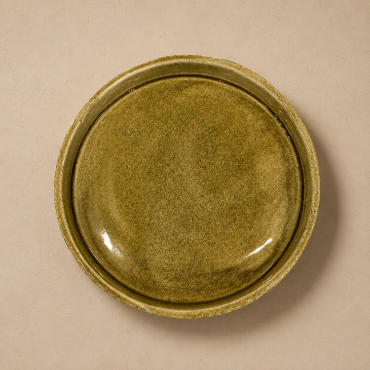 Side view of a handmade ceramic dish with organic carved surface and rustic detail